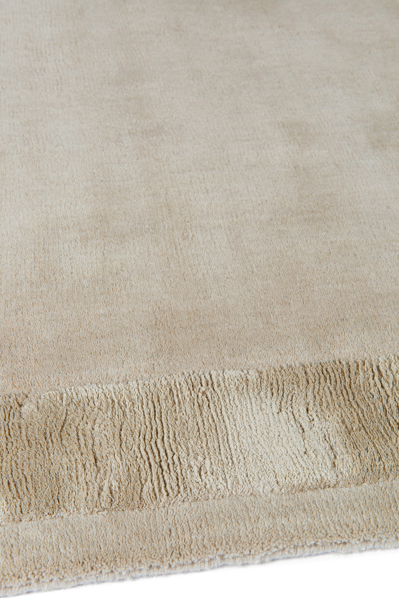 Close-up of Ashlar beige wool rug with bordered texture